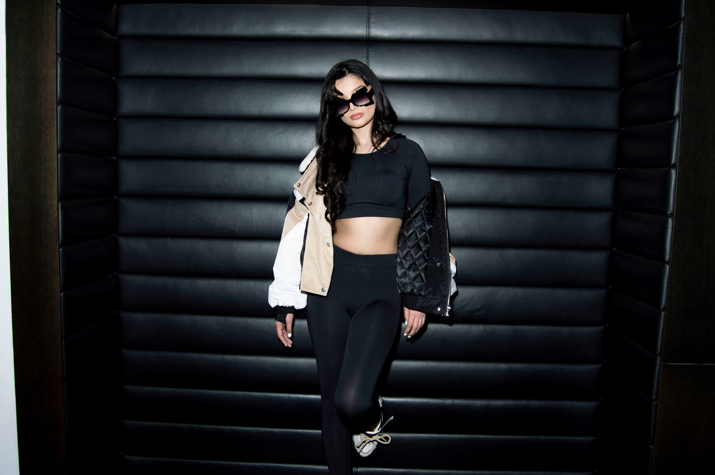 Girl wearing our Kaliyah windbreaker jacker over black Sia athletic set in a booth.