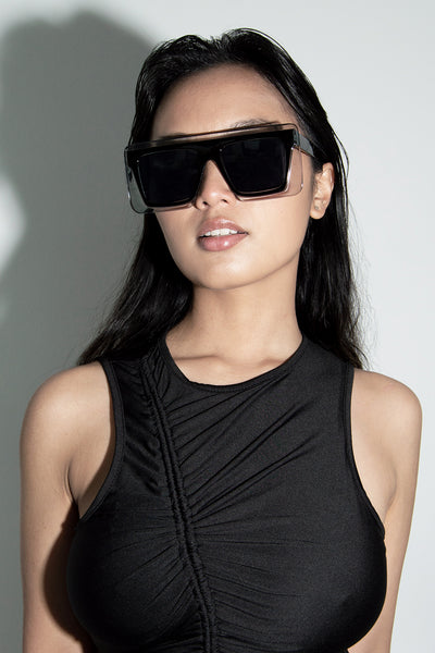 Model wearing our Mirai black square sunglasses with our black Kiera dress front view.